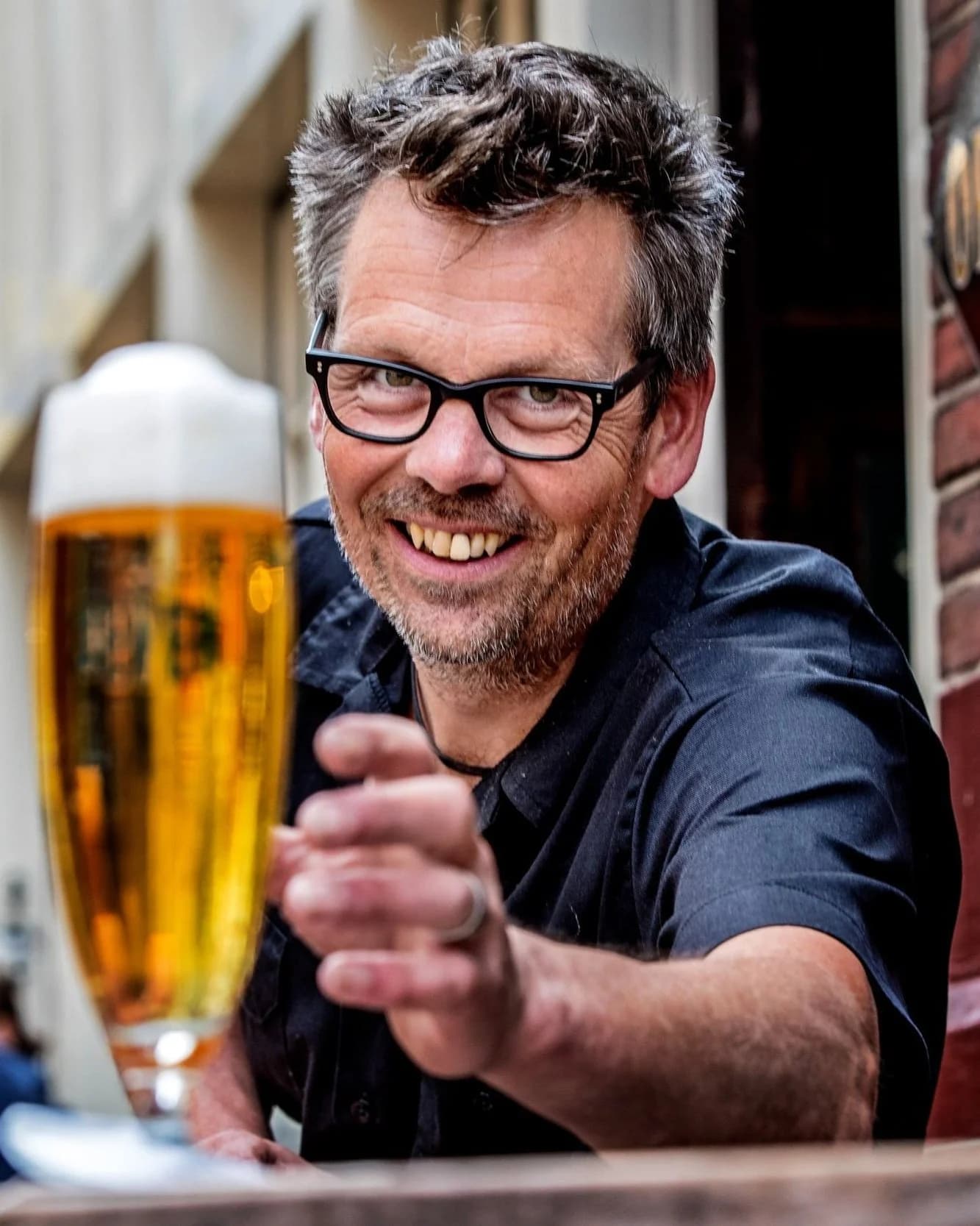 Man met zwarte bril holding beer